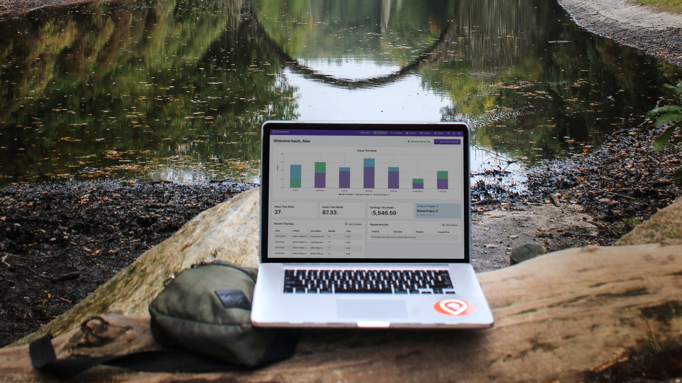A laptop running RemoteOne, resting on a log beside a lake